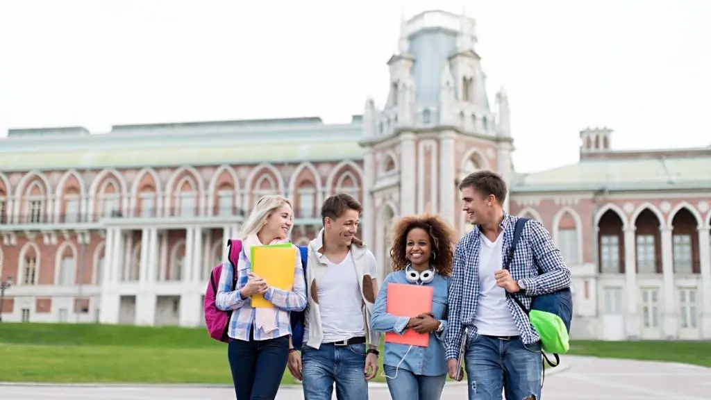 University students walking together on campus with books and backpacks